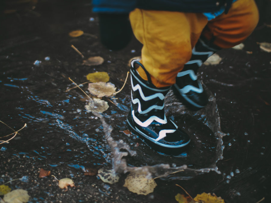 Child wearing wellington boots splashing in a puddle. Saving for a rainy day. Inheritance tax